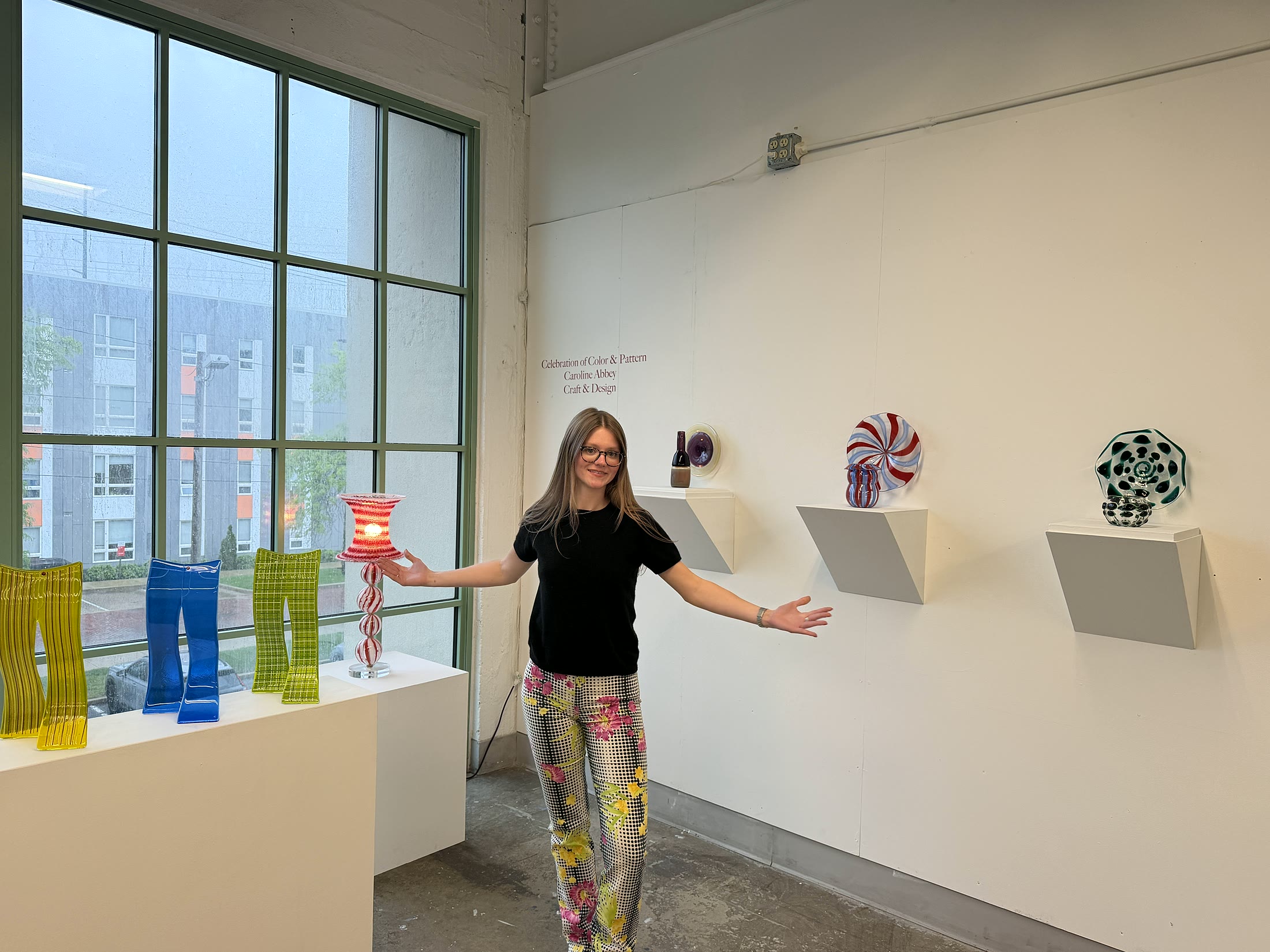 Caroline Abbey with colorful glass works in a gallery setting